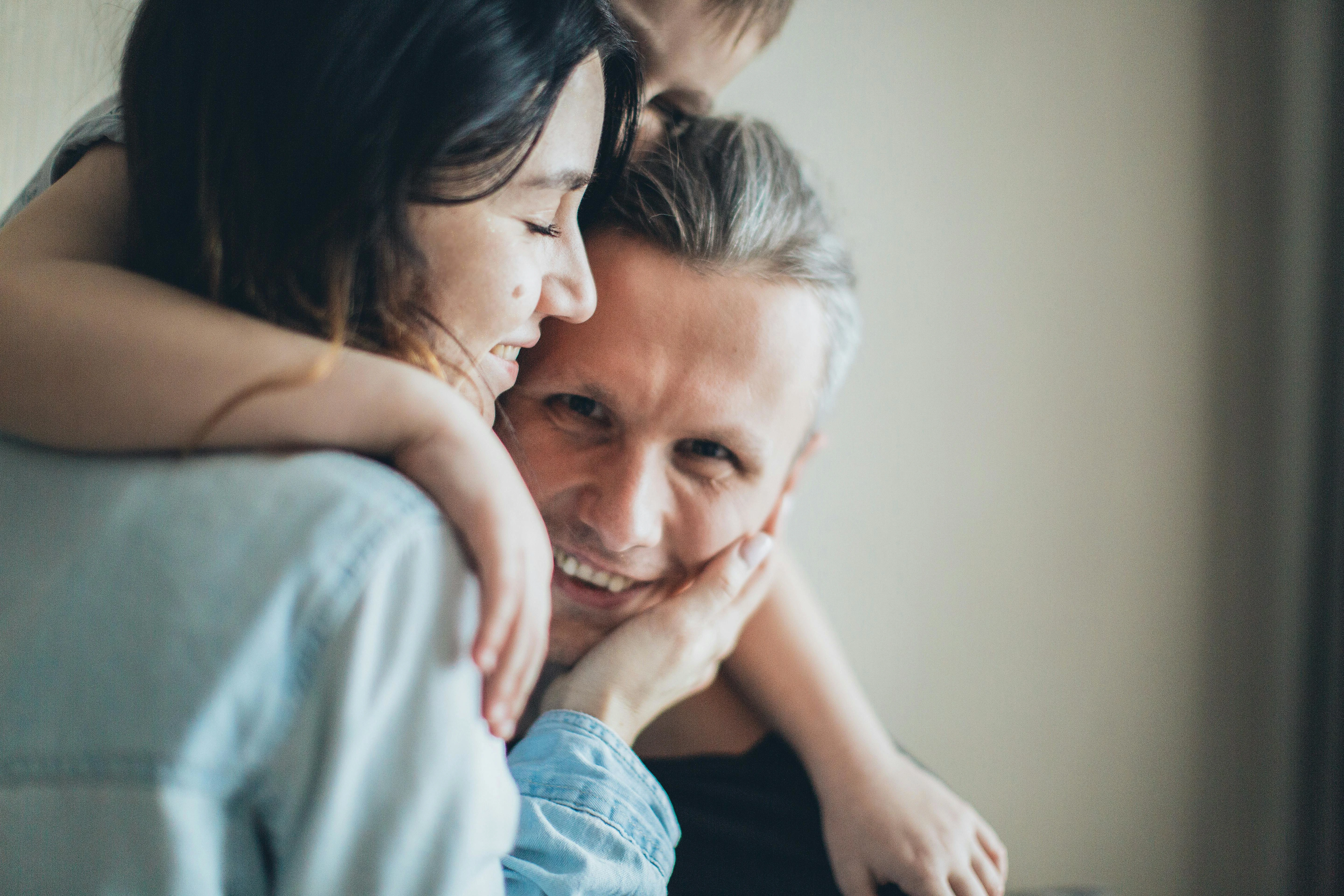 Woman and child hugging a man.