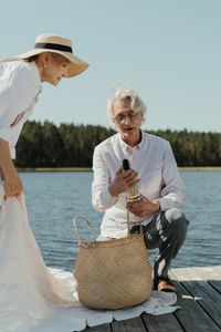 An older couple on a boat dock looking at a bottle of wine.