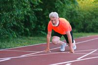 An older man at a starting line on a running track.